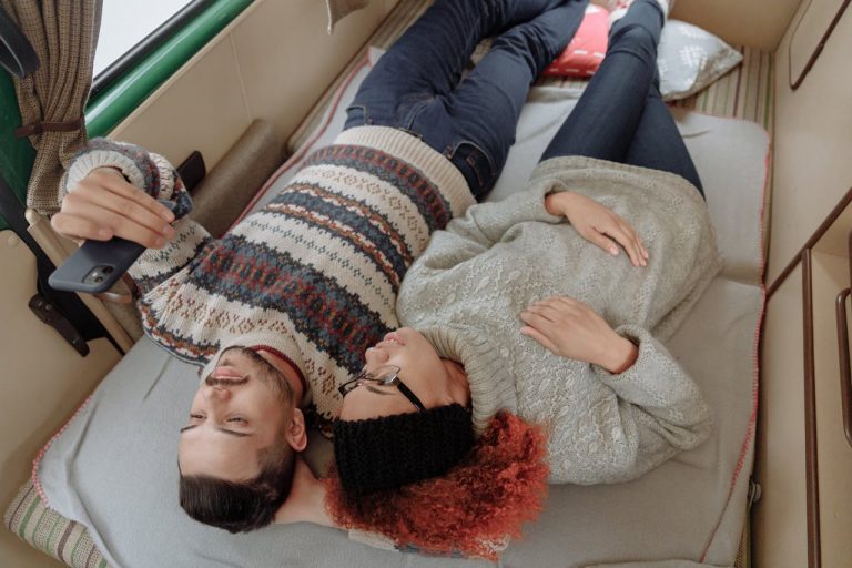 A couple enjoying a cozy moment inside a campervan, snapping a selfie together.